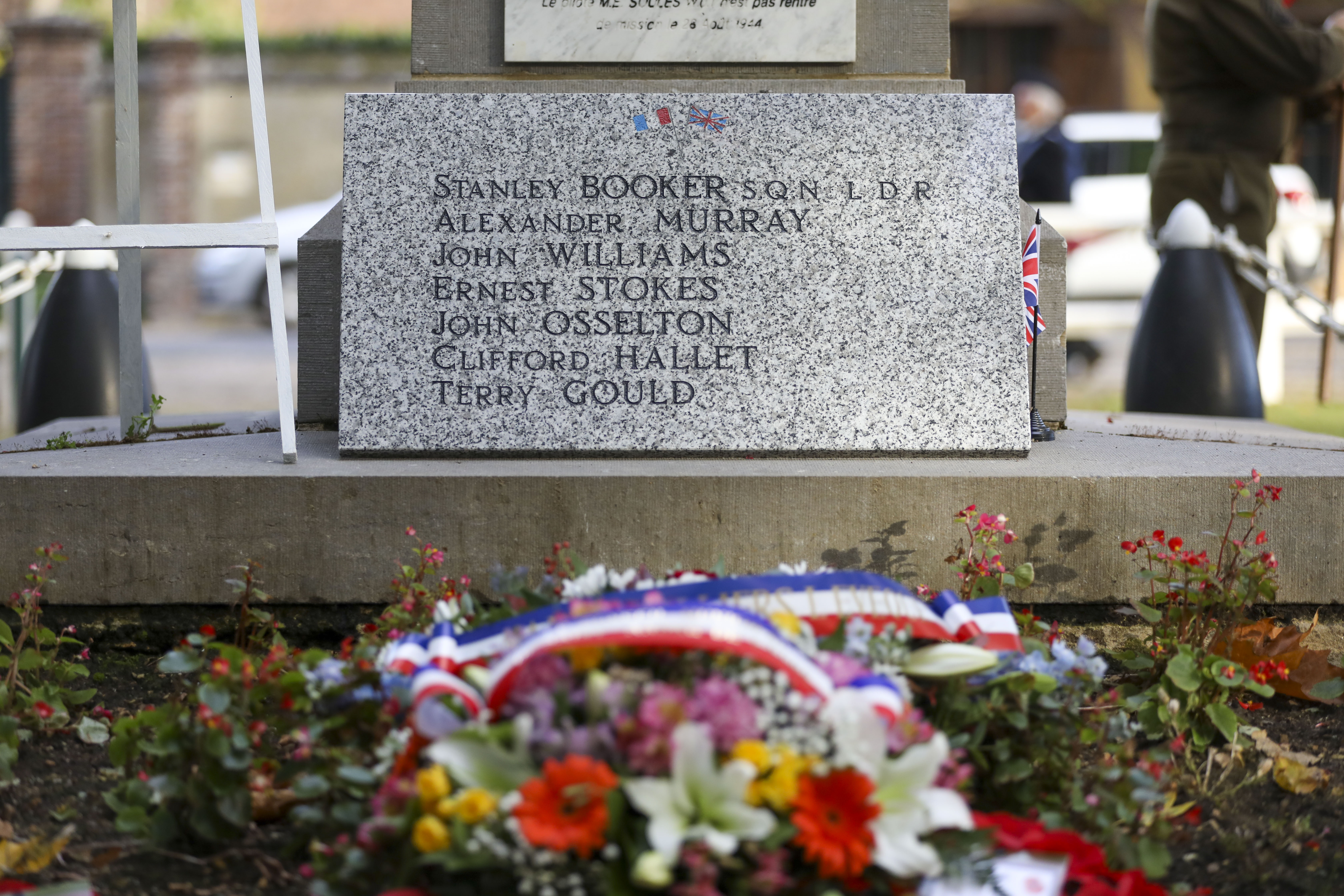 Memorial headstone with names etched on and flower wreath.